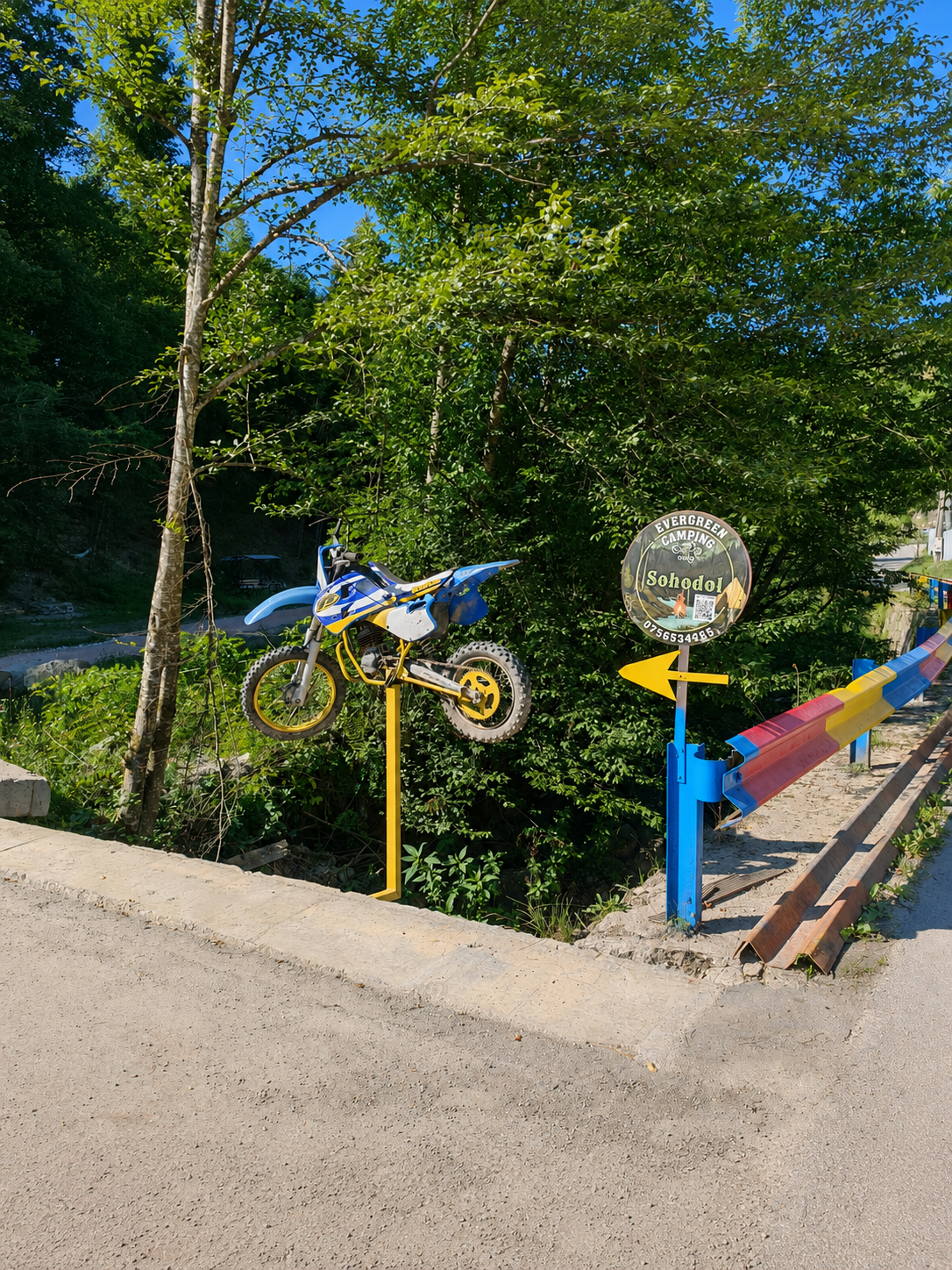 Intrarea in camping, marcata cu o motocicleta de cross pe stalp