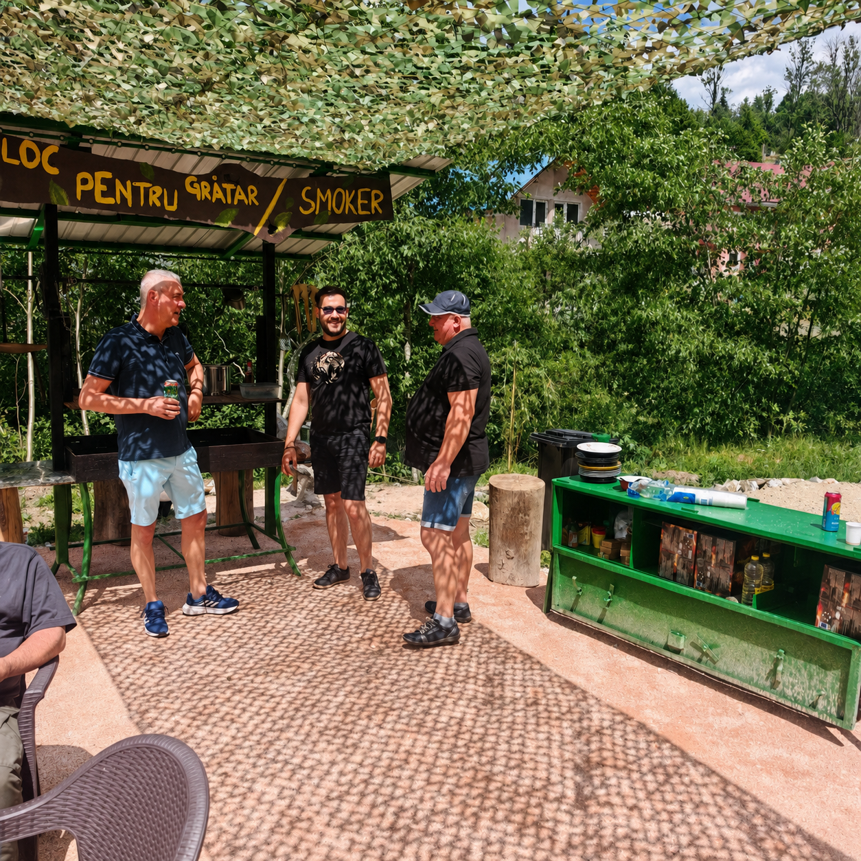 Zona acoperita de gratar si smoker din camping, cu motociclisti la masa